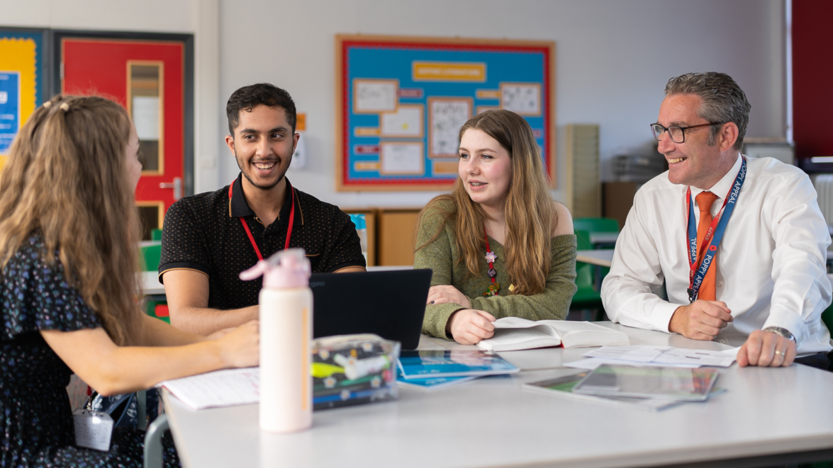 Industry_Marketing_Early_Careers_Article_Apprenticeships_Info_Image_Box_4 A group of students sat talking to their adviser in a classroom