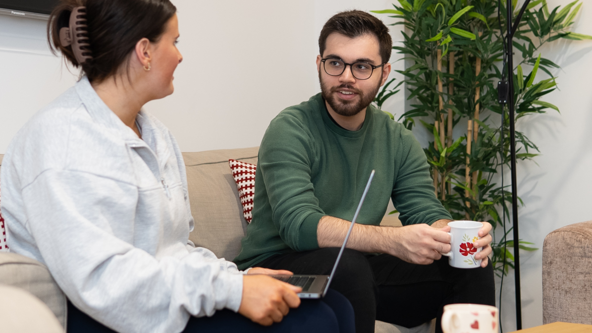 UCAS_Media_Articles_Accommodation_Further_Reading Two people sat together on a couch, focused on a laptop in front of them, sharing a moment of collaboration.